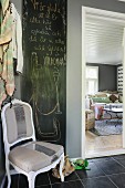 Handwritten congratulations on blackboard behind renovated chair with silver stripe in hallway with black tiled floor