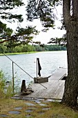Mit Platten gepflasterter Weg führt zu einem einfachem Holzsteg an idyllischem See