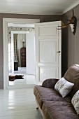 View from cosy living room with white wooden floor and reindeer antlers of bear-skin rug in hallway