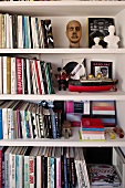 White bookshelves with small busts and a model of a ship