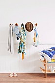 Various accessories (cloak, clothing, hat, bag) hanging on wooden wall hooks