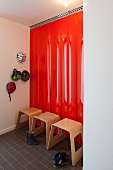 Modern wooden stools against red lacquered panels and cycle helmets hung on wall