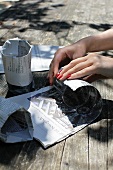 Lady's hands with red fingernails wrapping up glasses in newspaper