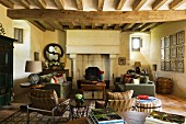 Vintage-look armchairs with metal frames and sofa set in front of open fireplace with chimney breast on columns in rustic interior