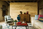 Traditional, Rococo-style armchair and sofa around modern coffee table in front of wooden partition in rustic interior