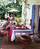Gartenterrasse mit Terrakottafliesen, geöffneter Terrassentür mit blauen Jalousien und einem gedeckten, festlichen Tisch