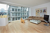 Großzügiger Wohnraum im Designer-Loftstil mit Blick auf Stadtkulisse durch die Glasfassade