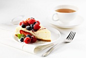 A slice of cheesecake with berries and a cup of tea