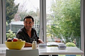 Man having a coffee break at a modern table in front of terrace windows