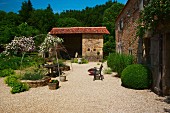 Simple country house and barn in open Mediterranean garden with seating area on gravel terrace