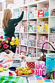 Woman in front of shelves of colourful boxes in a shop