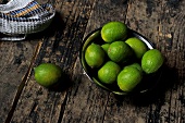 A bowl of limes on a wooden surface