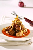 Roast pork with onions on a bed of tomato sauce