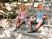 Brother and sister sitting on wooden steps, portrait