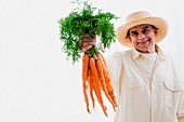 Älterer Mann hält ein Bund Karotten