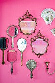 Collection of mirrors and hand mirrors on pink wall