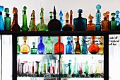 Pretty coloured glass bottles and vases on partition shelving