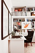 Corner office area - black leather armchair at white desk and fitted shelving