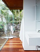 Modern sink in open-plan bathroom area of residential house with view of garden