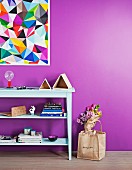 Pale mint-green shelves below painting of colourful triangles on bright purple wall