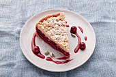 A slice of cherry crumble cake with cardamom pods