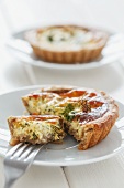 A mini quiche with herbs with a bite taken out