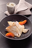 Apricot parcels with apricot pieces and icing sugar in a black dish