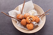 Deep fried dough balls with a sweet filling in a beige dish