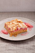 A piece of rhubarb cake with meringue and almonds on a white plate