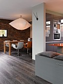 Offener Wohn- und Eßbereich mit grauer Einbauküche eines Architektenhauses mit dunklem Parkett und weißer Wandscheibe mit Uhrzeiger