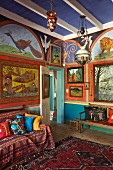 Kunstvoll mit Tiermotiven bemalte Wände, Orientteppich und gemusterte Textilien auf dem Sofa in einem Wohnraum