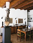 African sculptures, some on pedestals and sideboard, in dining room with wood-beamed ceiling and modern atmosphere