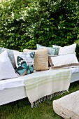 White cushions with patterns and butterfly motifs on bench in garden
