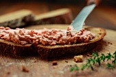 Liver sausage being spread onto a slice of bread