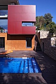 Moderne Architektur mit farbigen und gläsernen Fronten und einer Holzterrasse mit Swimmingpool