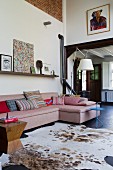 Animal-skin rug and sofa in open-plan interior of renovated country house