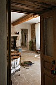 Blick durch offene Tür in den Wohnraum eines südfranzösischen, restaurierten Landhauses mit rustikalem Natursteinboden