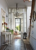 Elegante Diele mit barockem Wandtisch, Kronleuchter und Treppenaufgang mit Steinstufen und Holzgeländer