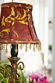 Table lamp with red and gold lampshade and beaded trim