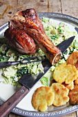 Veal knuckle on a bed of savoy cabbage with bacon and fried potatoes on a serving platter