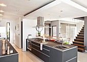 Freistehende Küchentheke mit grauen Oberflächen unter abgehängter Decke in modernem, offenem Wohnraum gegenüber Treppenaufgang