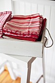 Stacked dish towels in a white vintage box on a stool