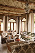 Moroccan-style living room with wood-beamed ceiling, arched windows and comfortable sofa combination