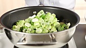 Garlic, broccoli and spring onions being added to a pan