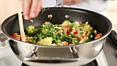 Vegetable couscous being sprinkled with parsley