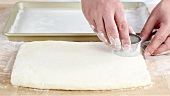 Pastry for buttermilk biscuits being rolled out and circles being cut out
