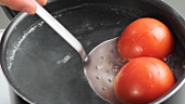 The tomatoes being removed from the boiling water