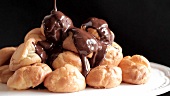 Chocolate sauce being poured over profiteroles