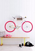 Bicycle hung on hall wall above a bench