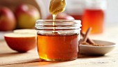 A honey spoon being dipped into a jar of honey